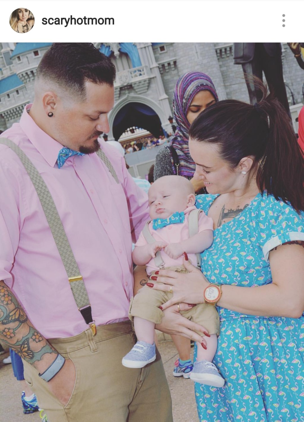 dad in pink, baby in pink and mom in blue dress with cinderella castle behind them