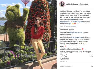 woman in red top, yellow pants in front of pooh topiary