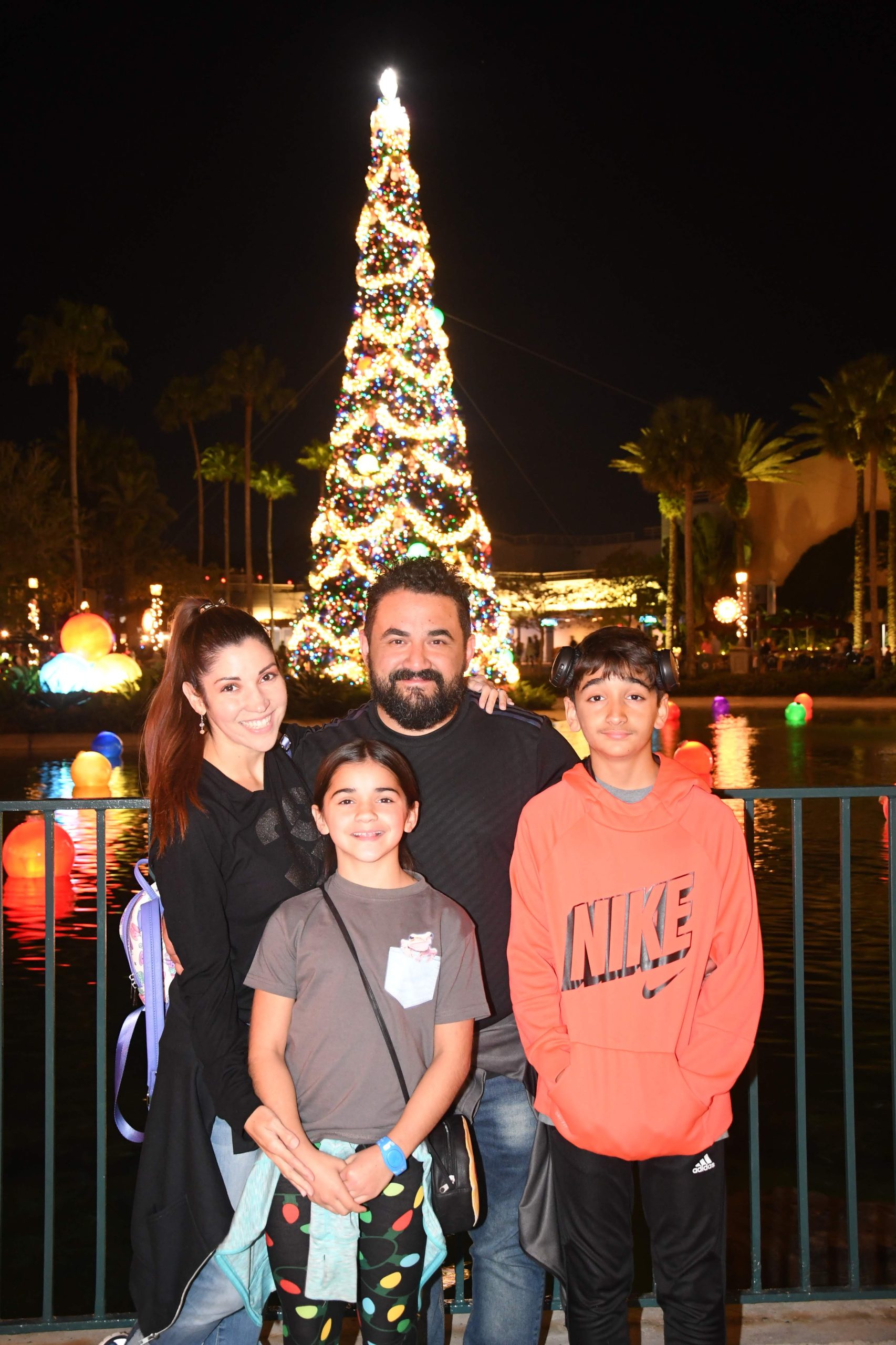 Disney's Hollywood Studios Christmas Tree family photo of family of four with water floating lights and tree behind them