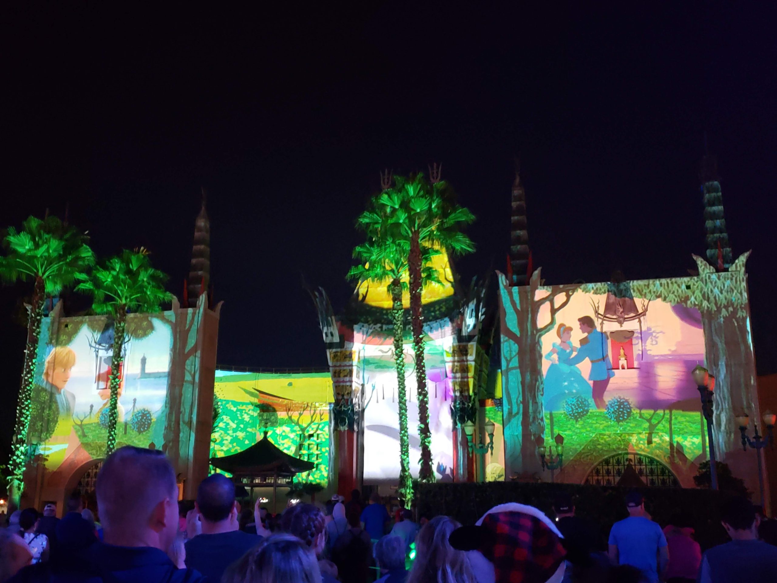 Jingle Bell Jingle Bam images of Disney Princesses projected onto the Chinese Theater in Hollywood Studios, palm trees lit up 