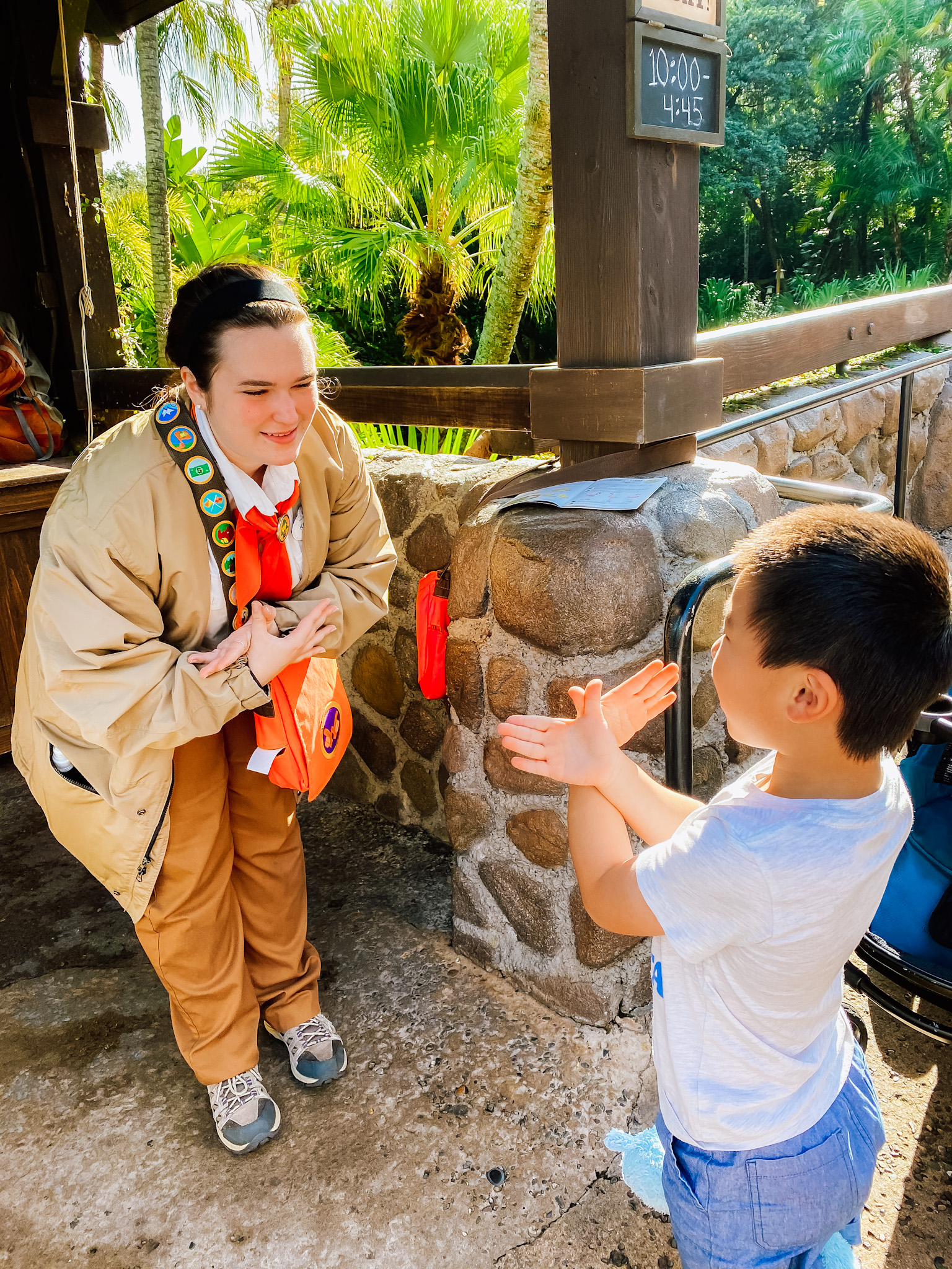 cast member and child doing the wilderness explorers call with their hands linked together