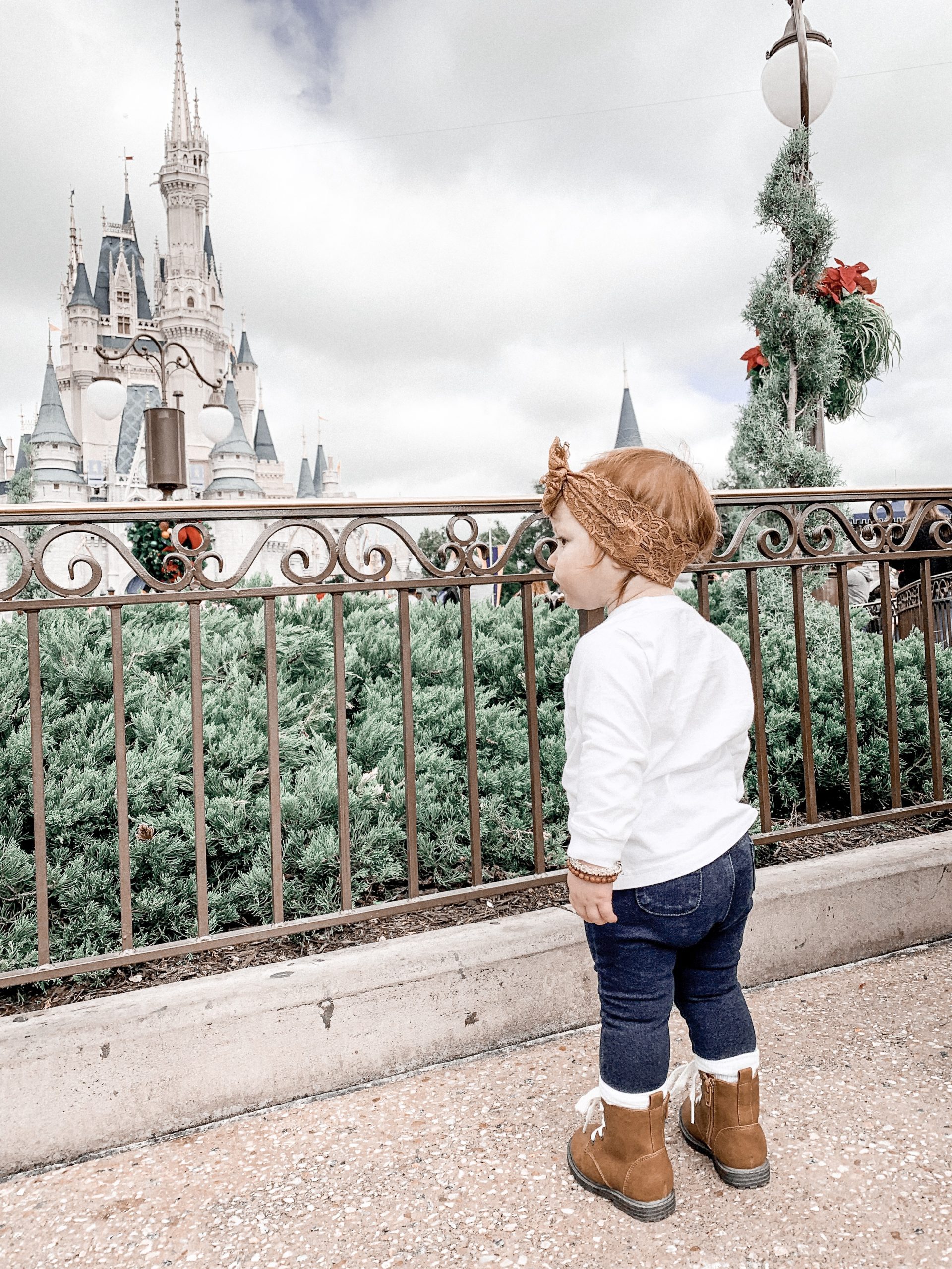 little girl in front of cinderella castle and fence