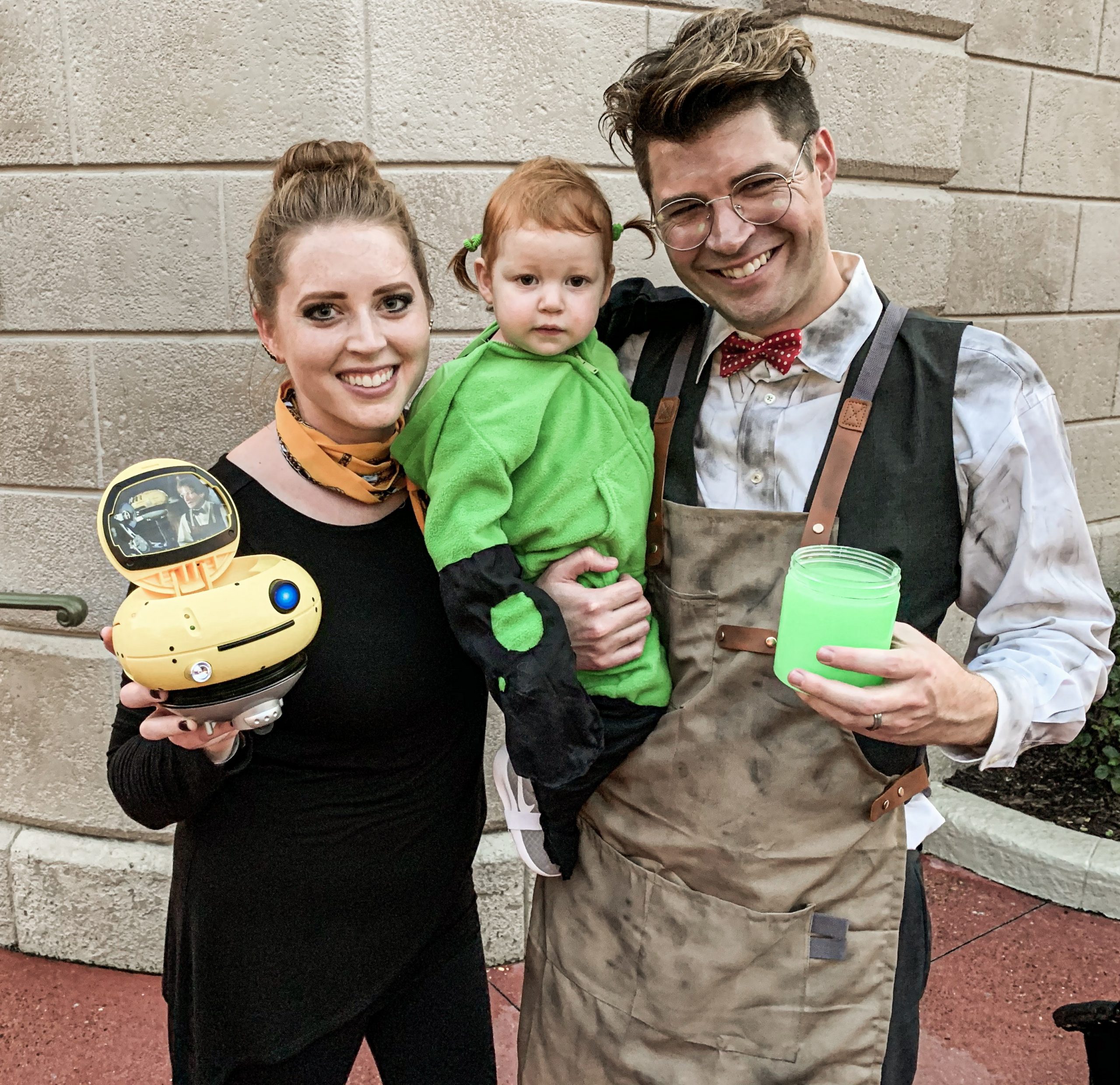 mom and dad dressed as characters from WALL-E and girl in neon green
