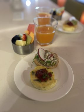 egg, avocado on toast, fruit and orange juice on a white tablecloth