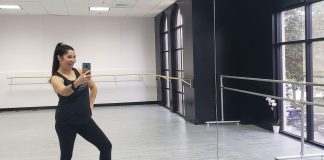 A latina mom is taking a mirror selfie at a dance studio
