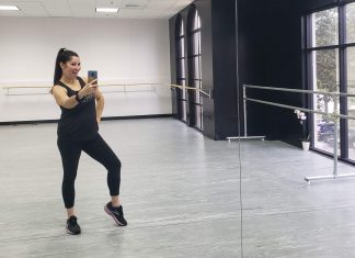 A latina mom is taking a mirror selfie at a dance studio