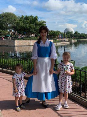Two little girls meeting Belle with lagoon and spaceship earth behind