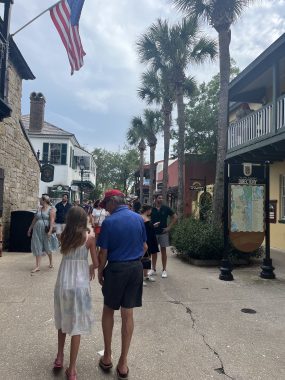 little girl with father-figure walking with other people in between rows of shops. St. George's Historic Walk, date night in St. Augustine