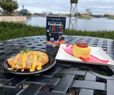 Festival of the arts passport with empanada and cheesecake on a table looking over the lagoon