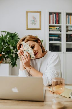 woman with money on her face, staring at the computer. Thinking about new year's resolutions