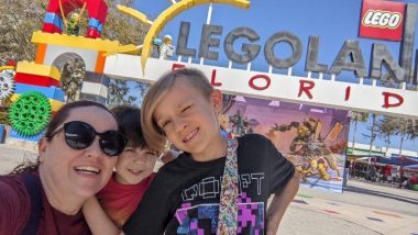 woman with sunglasses, one boy child in red, one boy child in black shirt in front of LEGOLAND Florida entrance sign