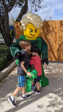 two boys hugging big green lego man character