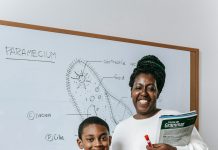 woman and child standing in front of a white board with a science lesson on it smiling at the camera. All to help kids thrive at school