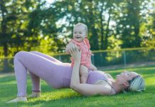 mom in workout clothes outside with baby on top of her, working out together finding gyms with childcare