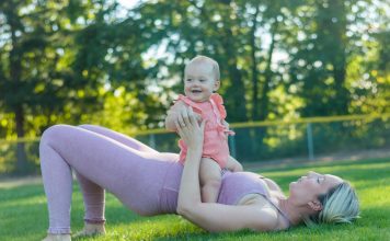 mom in workout clothes outside with baby on top of her, working out together finding gyms with childcare