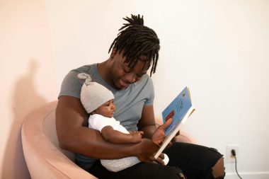 Father reading a book to his baby; black history month
